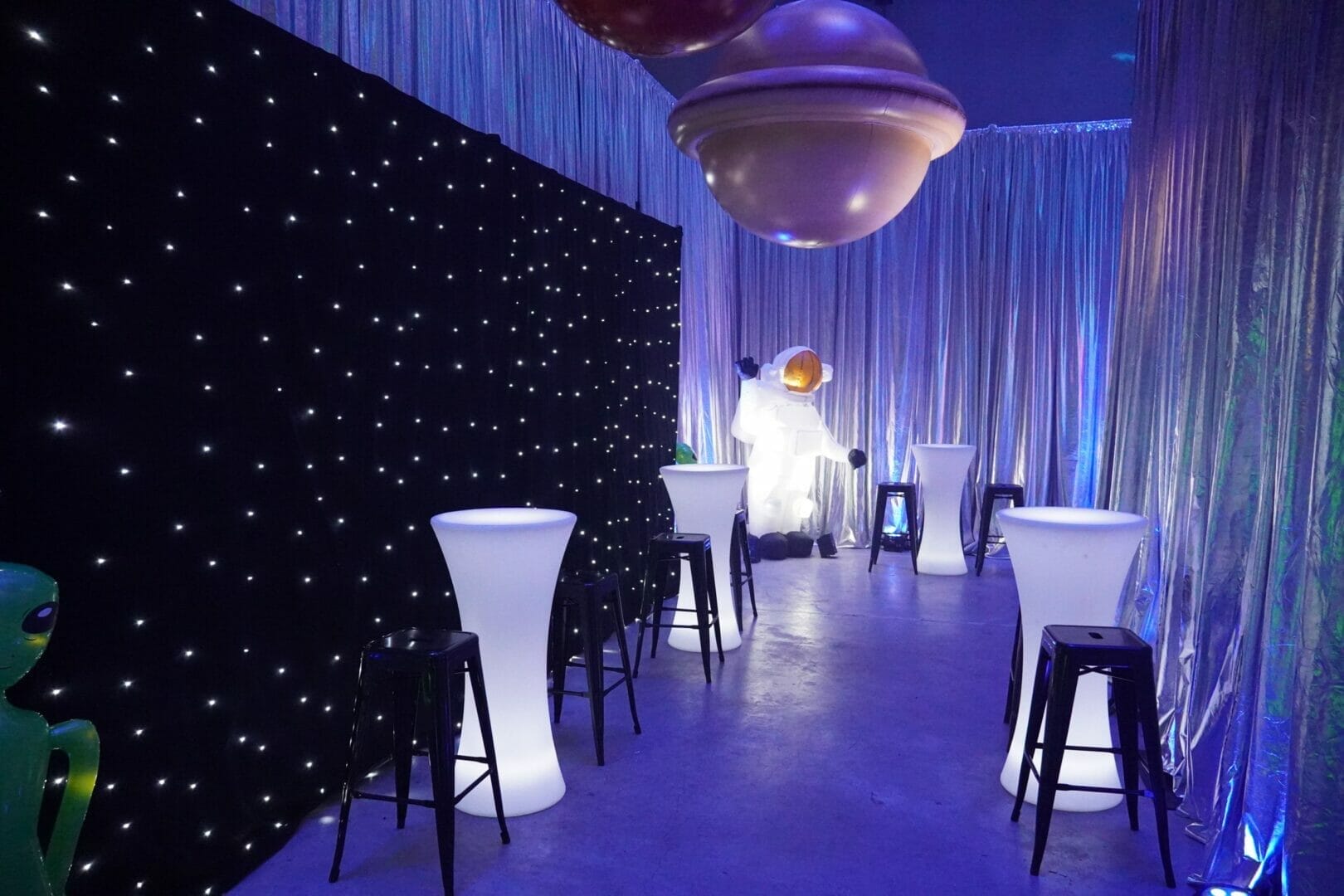 Star cloth and illuminated bar tables at space themed party
