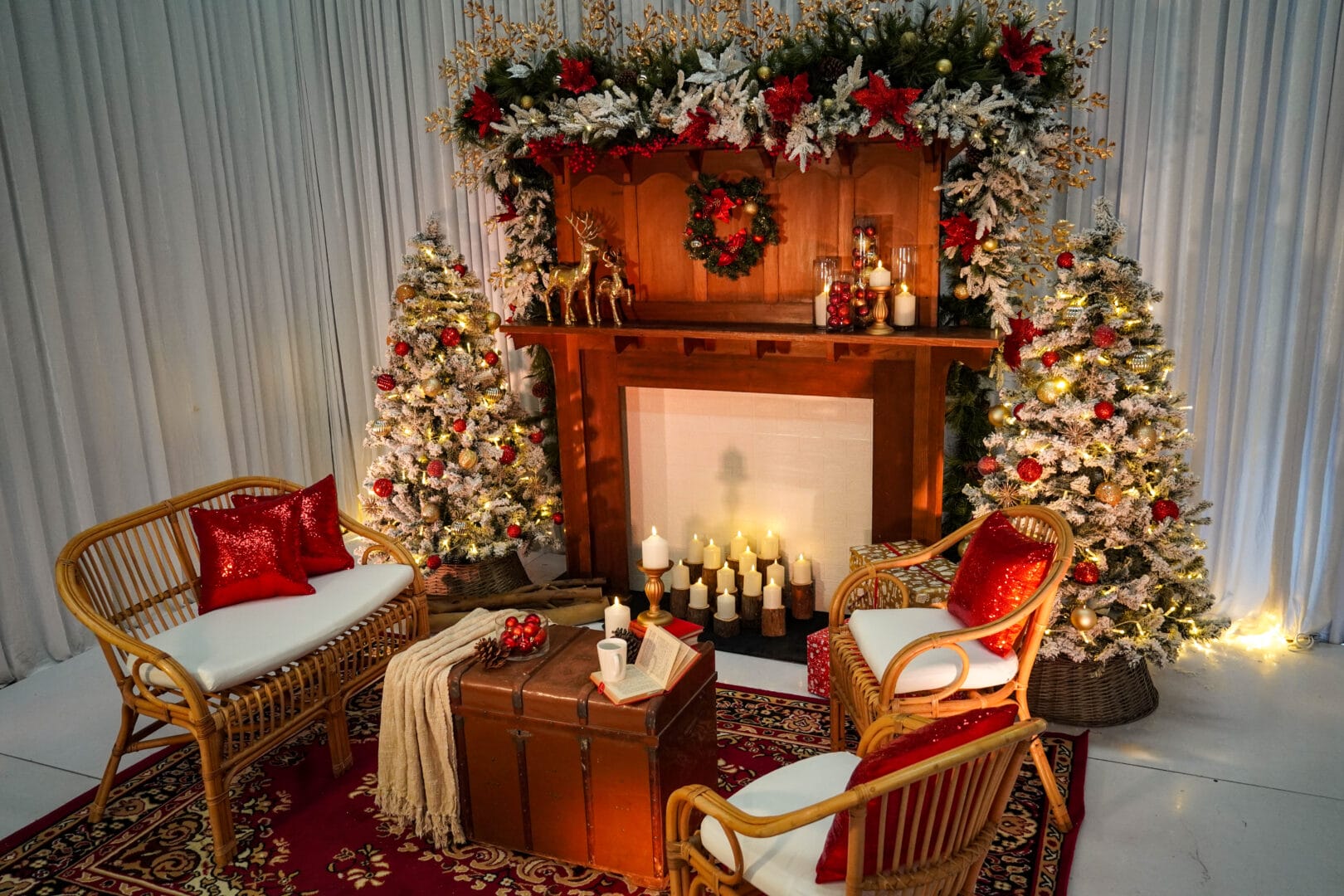 christmas themed setup featuring white frosted pine trees, ornaments, rattan furniture, and red cushions