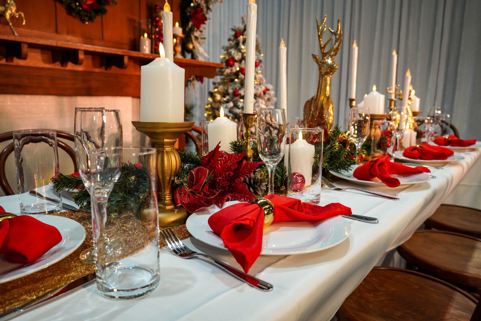 christmas themed table setup with candles, garlands, napkins, and themed decor