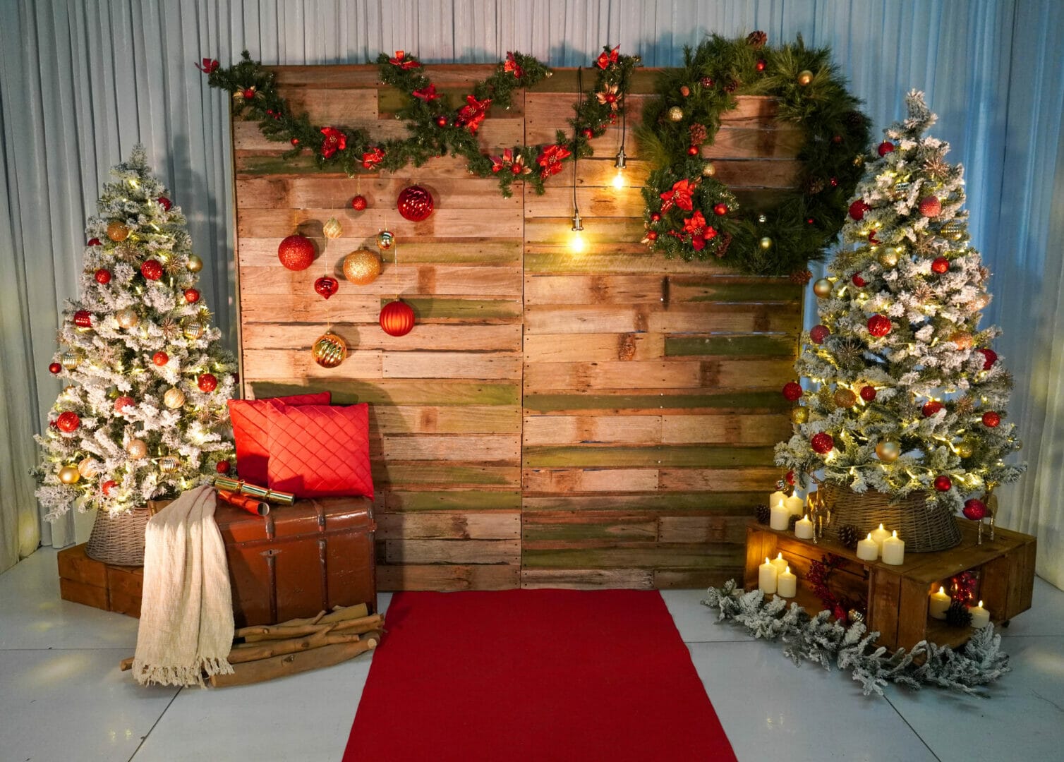 christmas themed rustic backdrop with ornaments, frosted pine trees, cushions, garlands and wreaths