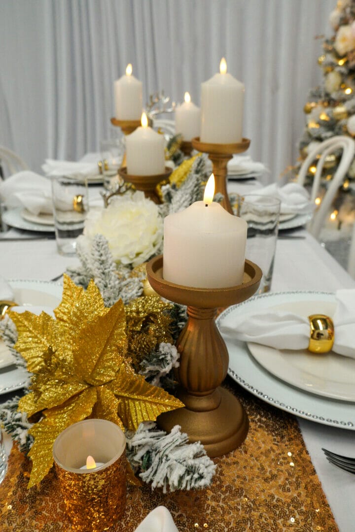 Christmas dining table setup featuring candles, gold leaves, flowers, and more