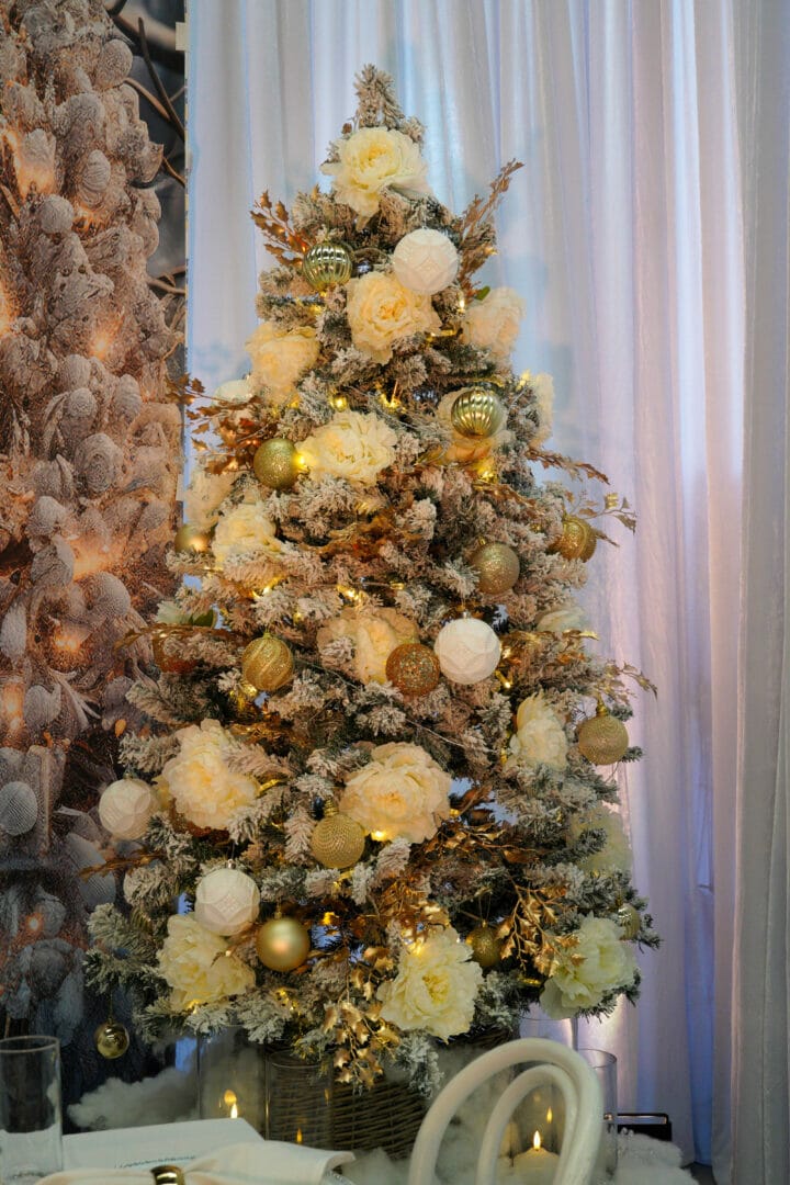 Gold and white decorated christmas tree with ornaments, flowers, and gold leaves