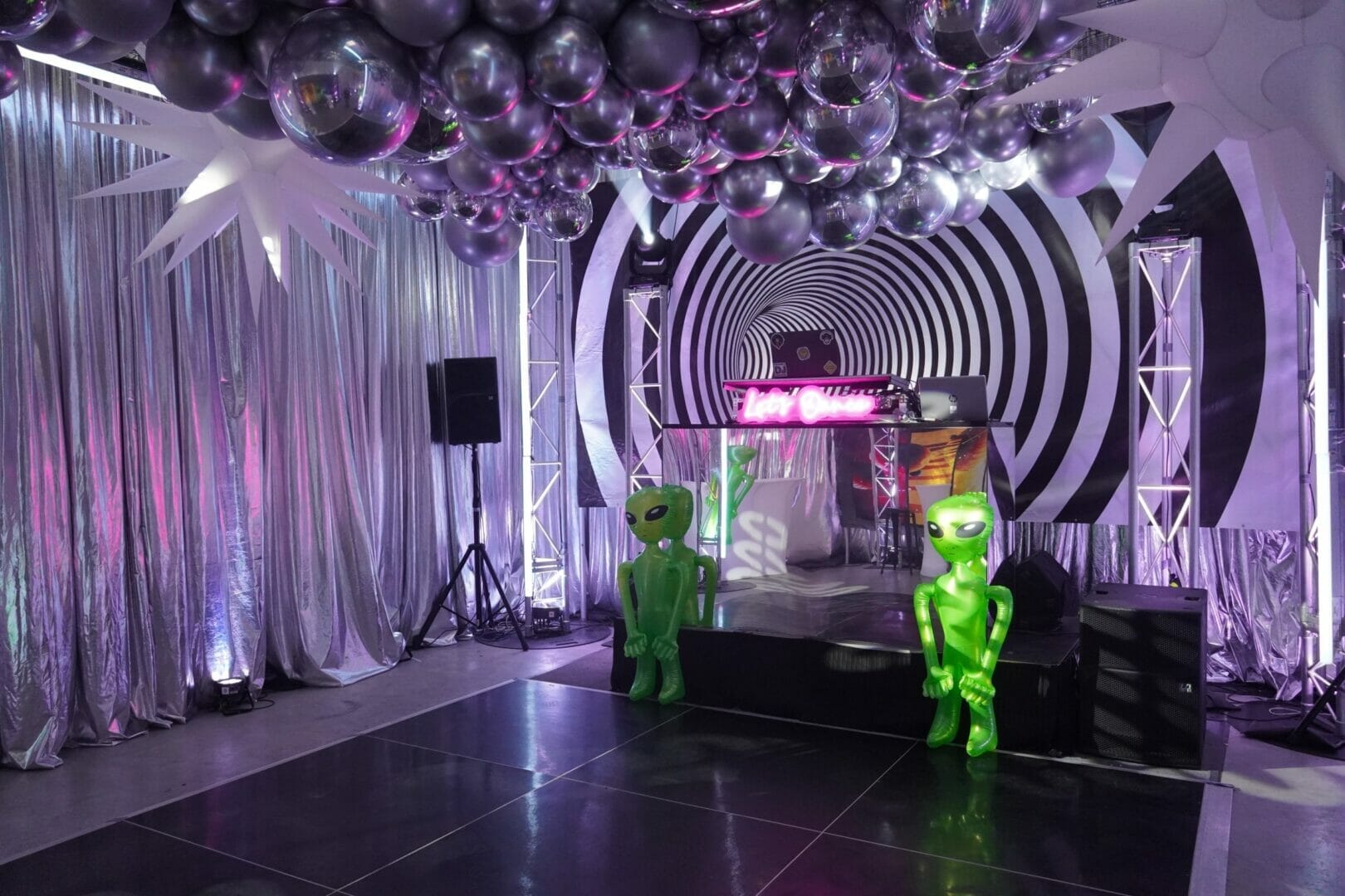Dance floor area of space themed party. Party lights, inflatable props, balloons, themed backdrops.