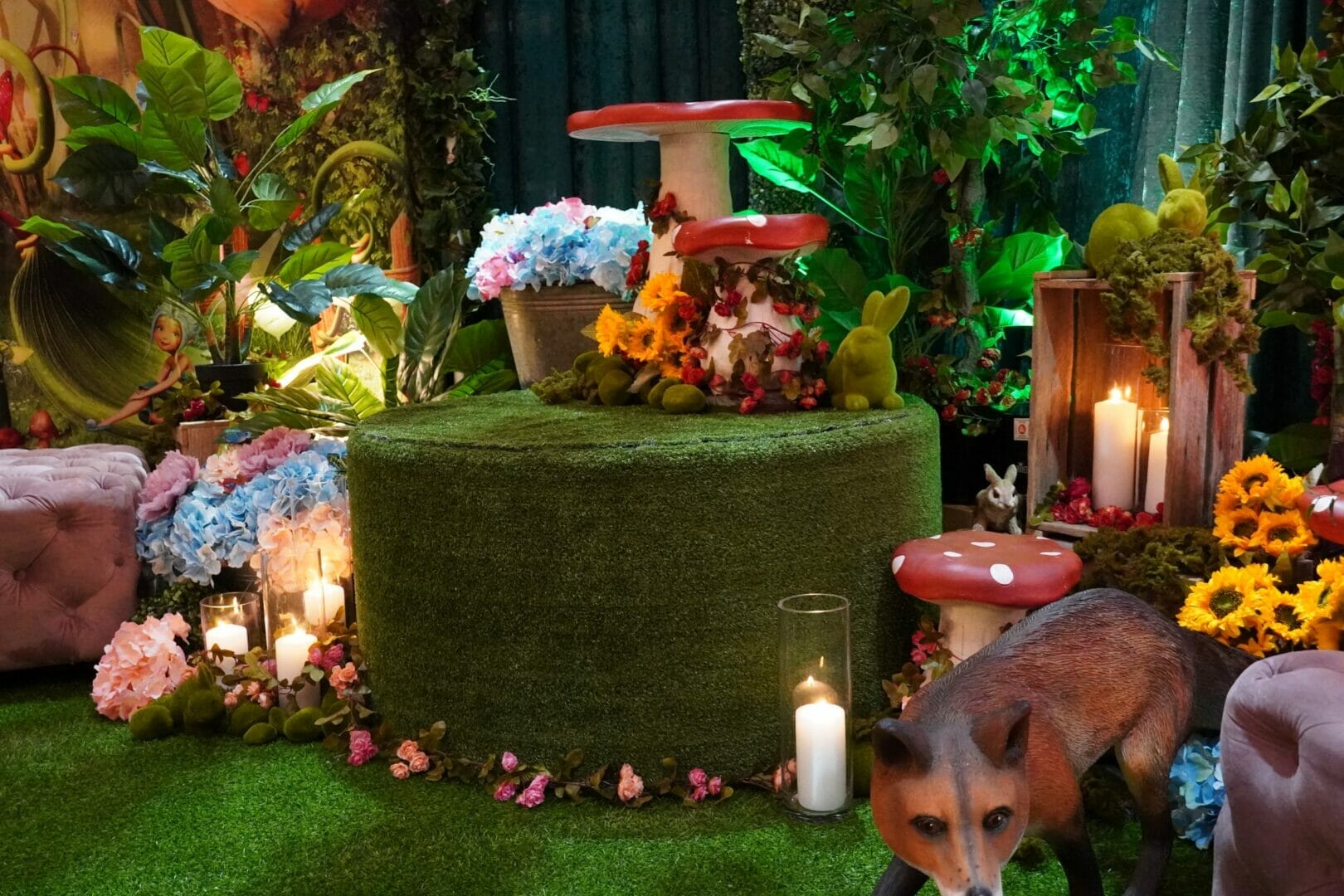 artificial flowers, grass ottoman, and themed props in enchanted garden themed setup