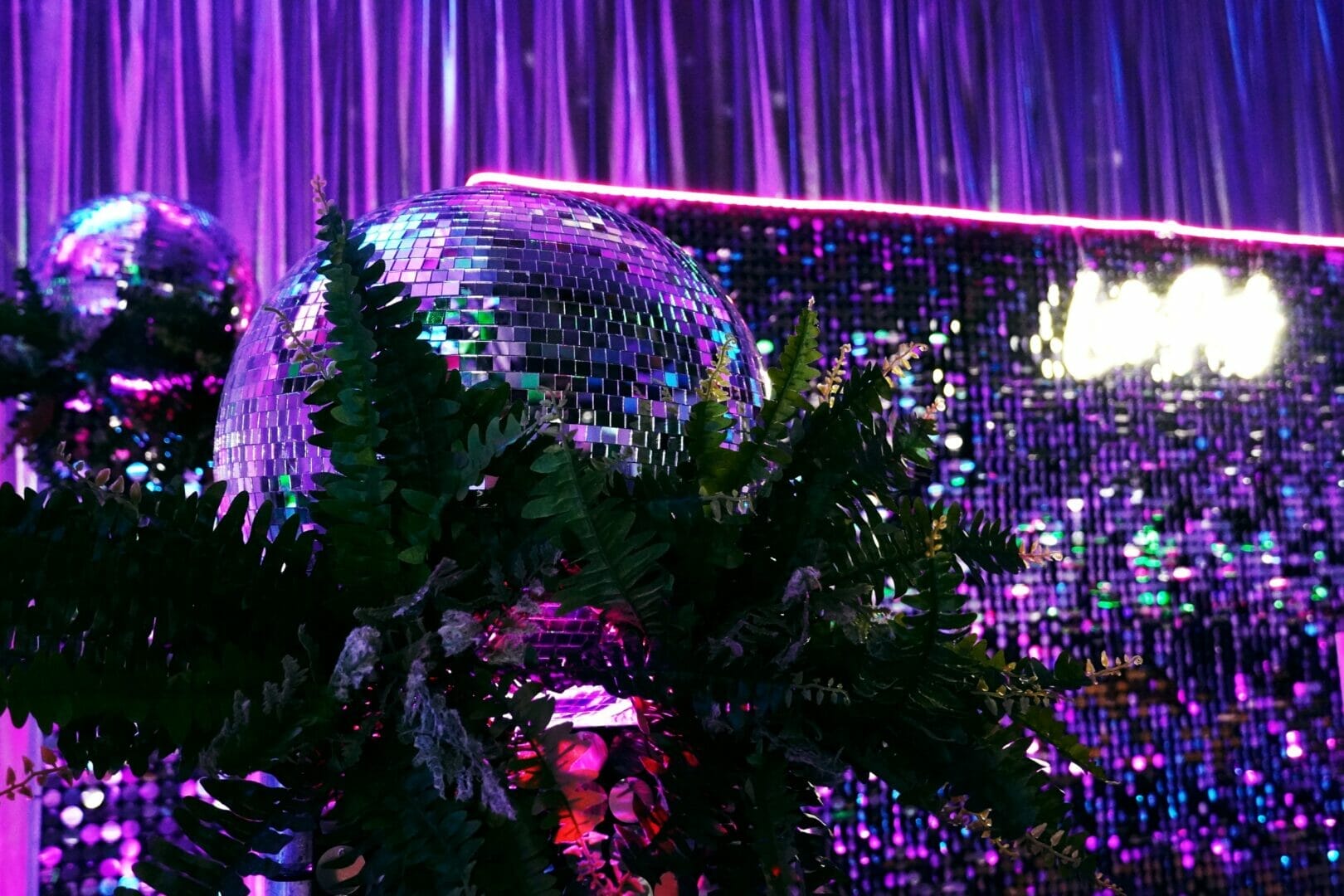 mirror balls, greenery, sequin panels, neon lights, neon sign at neon disco party theme