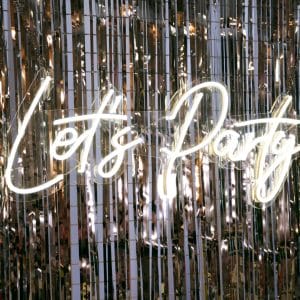 let's party neon sign with silver tinsel curtian