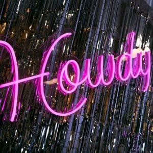 howdy neon sign and silver tinsel curtain