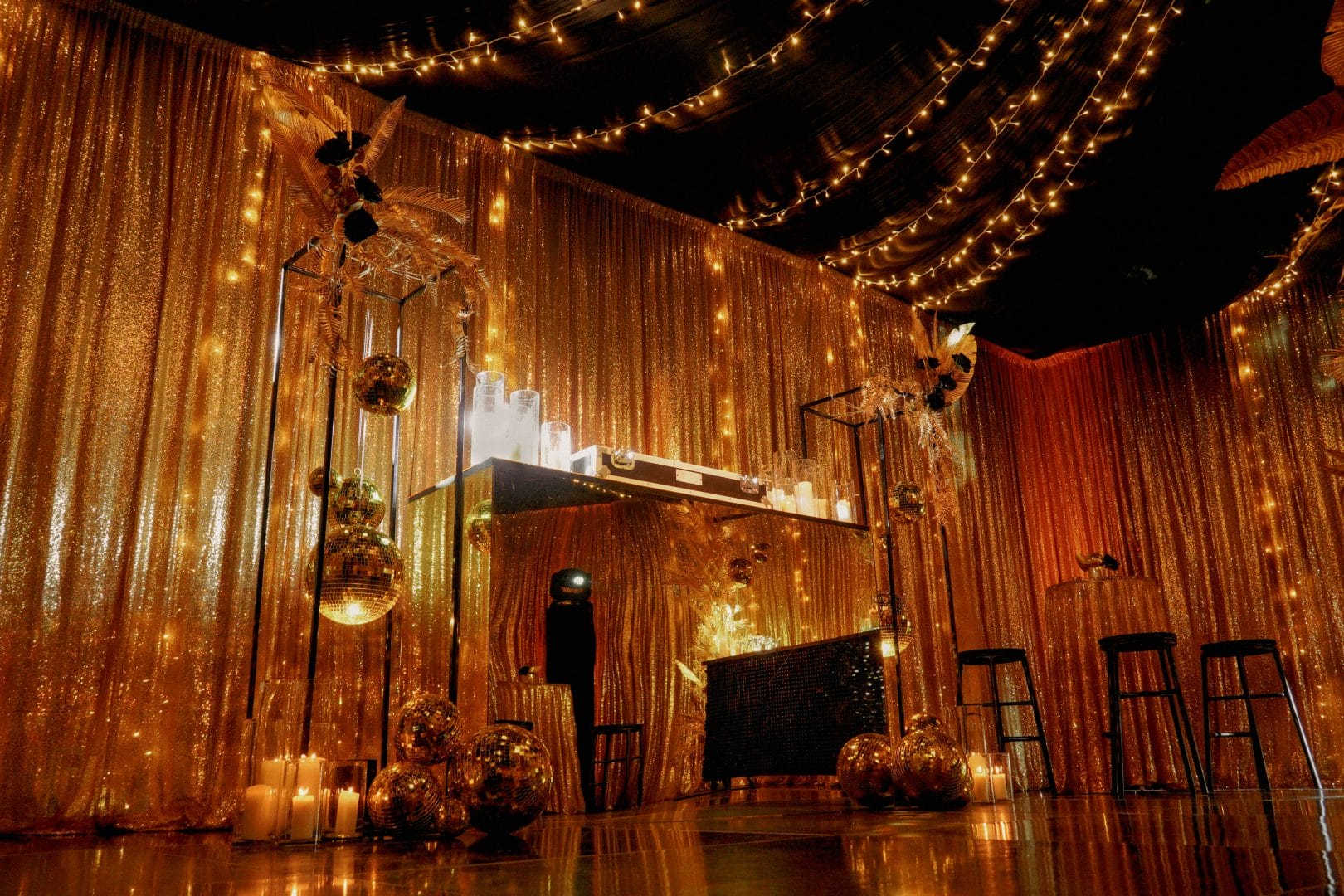 Gold acrylic bar and DJ booth with themed gold centrepieces, gold mirror balls, and gold sequin drape
