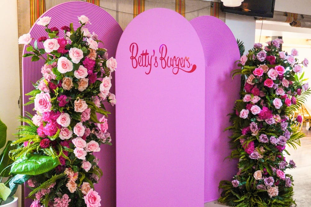 Betty's Burgers decal on pink rounded arches with floral pillars on either side