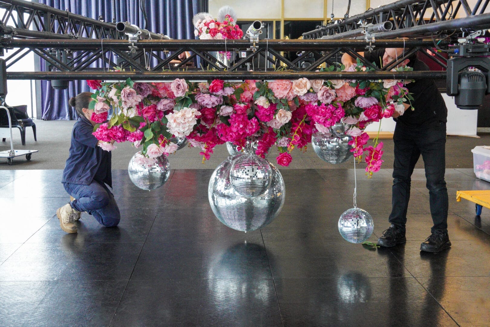 Setting up a pink floral and silver disco ball ceiling installation