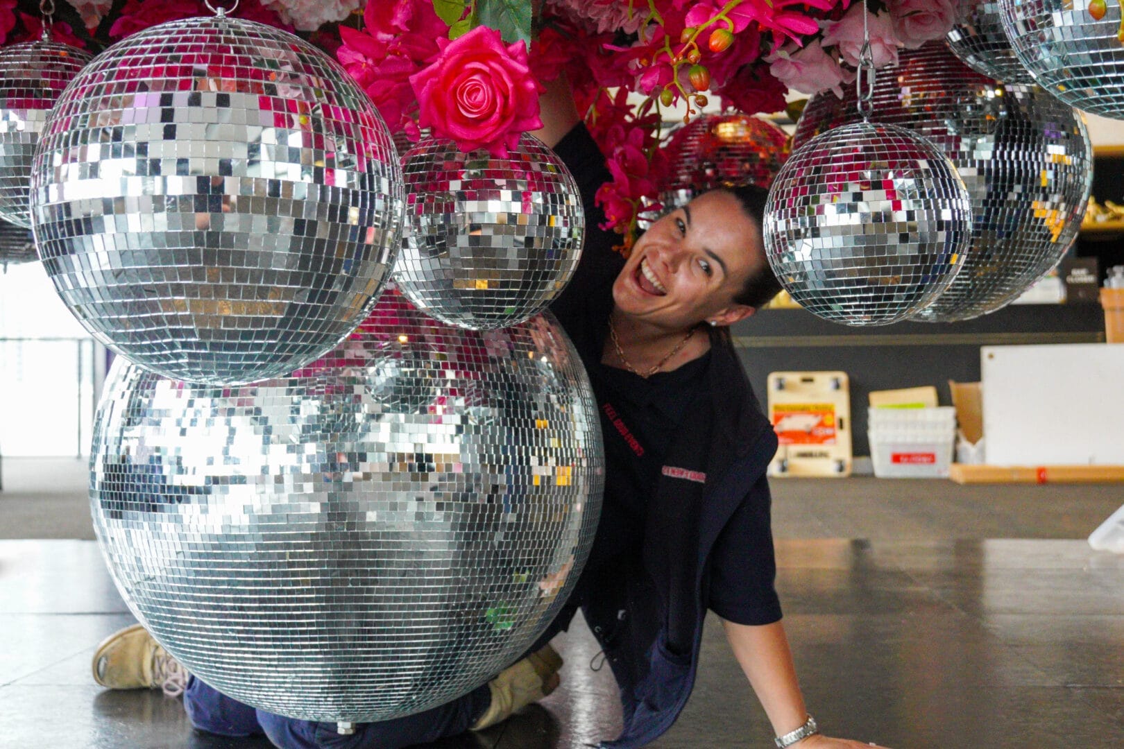 Emma setting up a pink floral and sliver mirror ball ceiling installation
