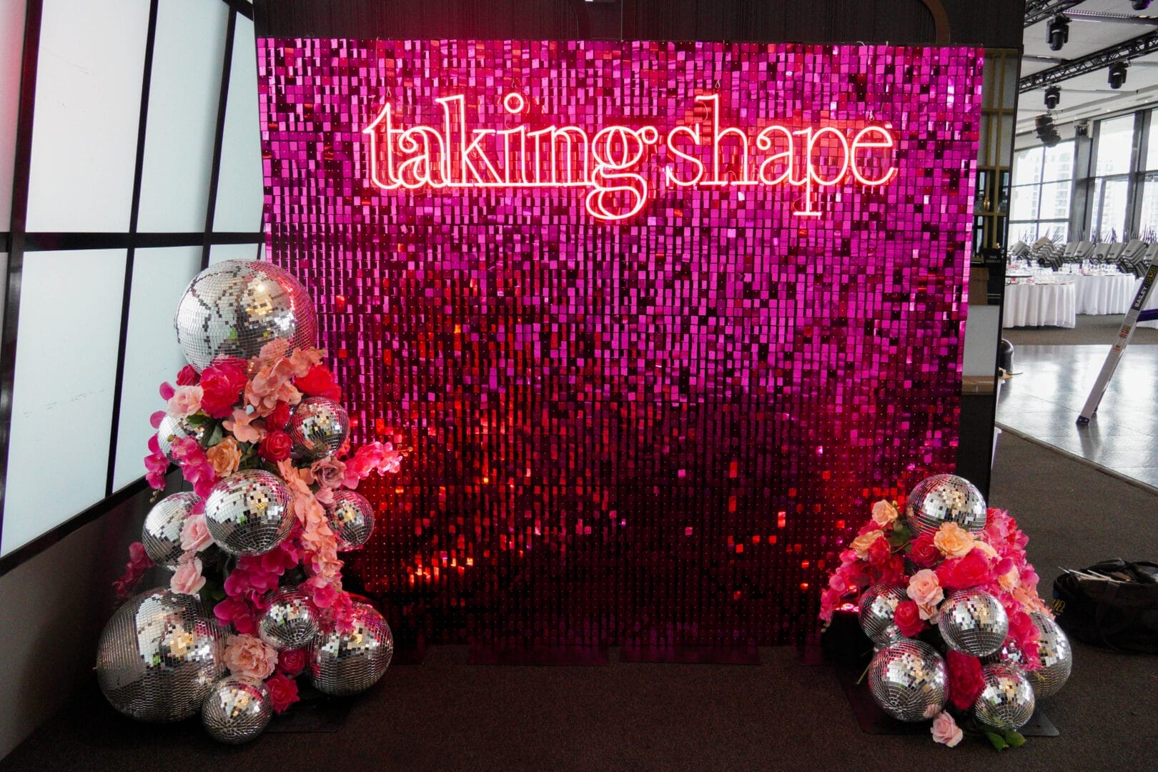 Pink sequin wall backdrop with a neon sign and mini floral and disco ball installations