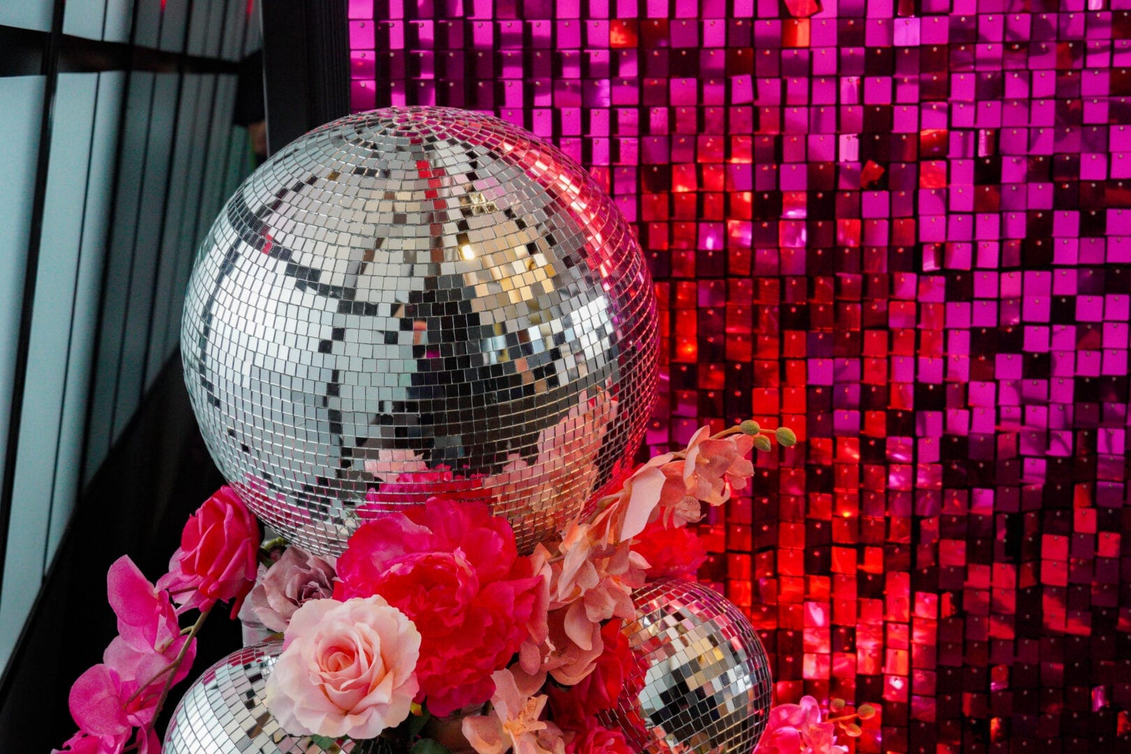 Silver disco balls, pink flowers, and a pink sequin wall