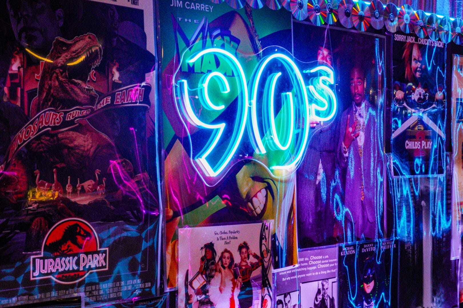 90s neon sign sitting on a backdrop of 90s movie posters