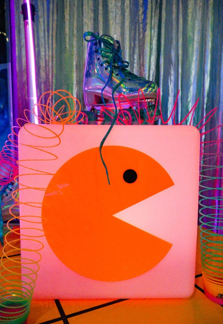 LED Cube with Pacman acrylic on it surrounded by slinkys and roller skates