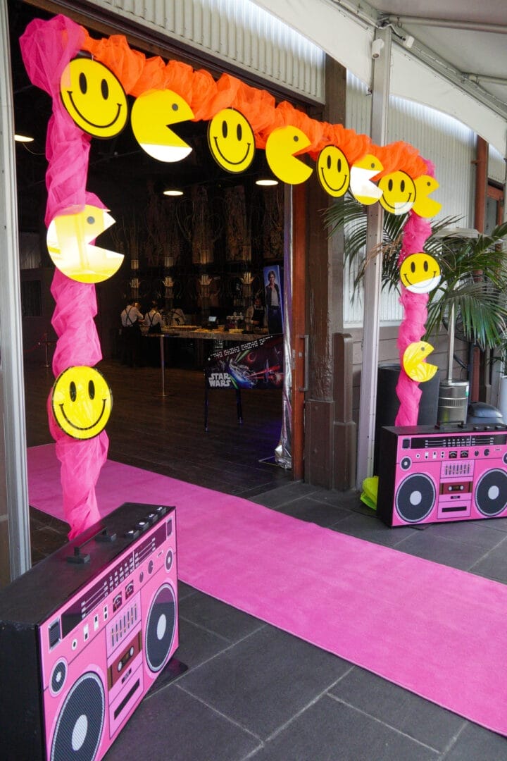 entranceway of 80s and 90ss themed party with themed acrylics, fluro tulle and pink carpet
