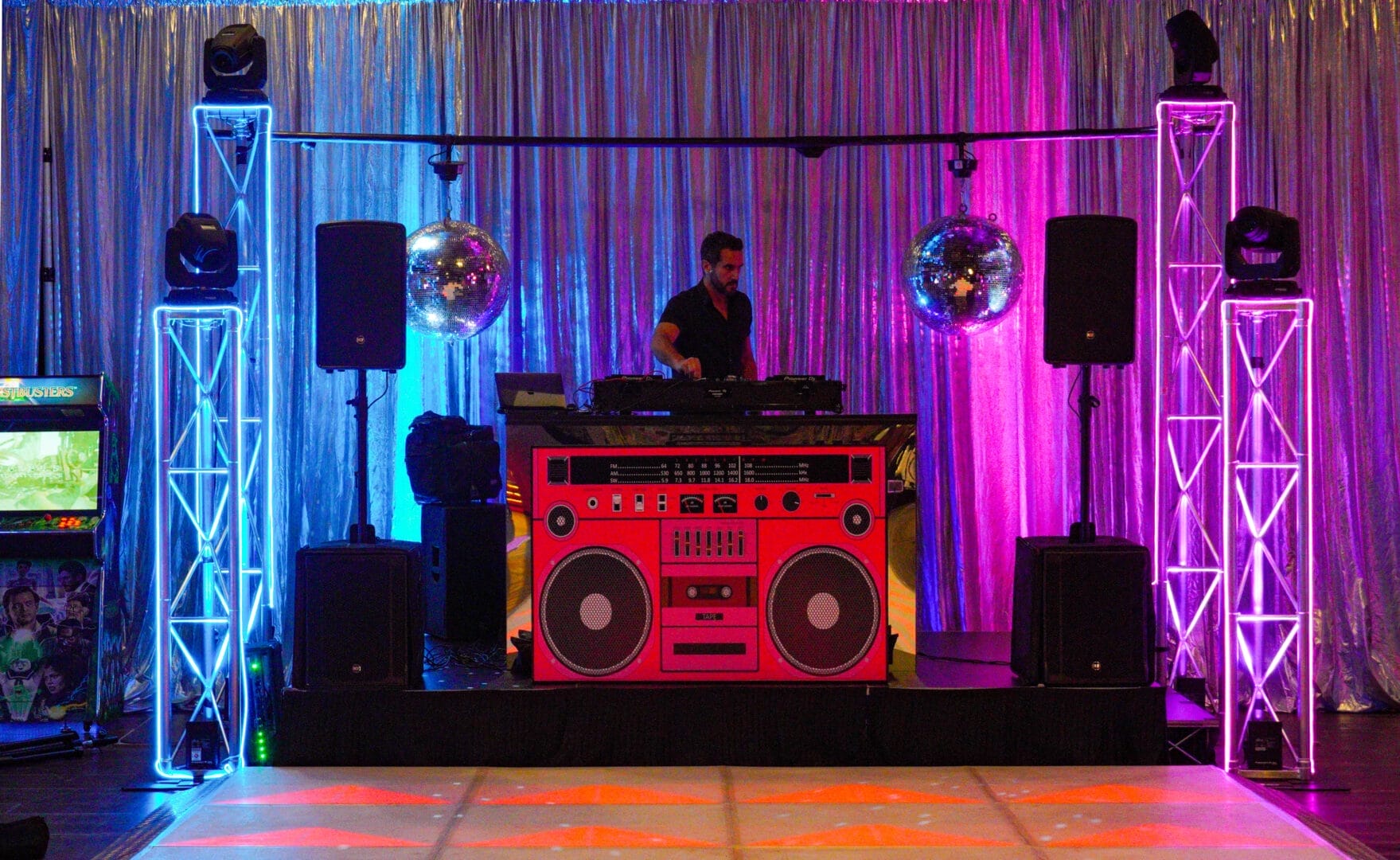 Pink stereo DJ booth with disco balls hanging above