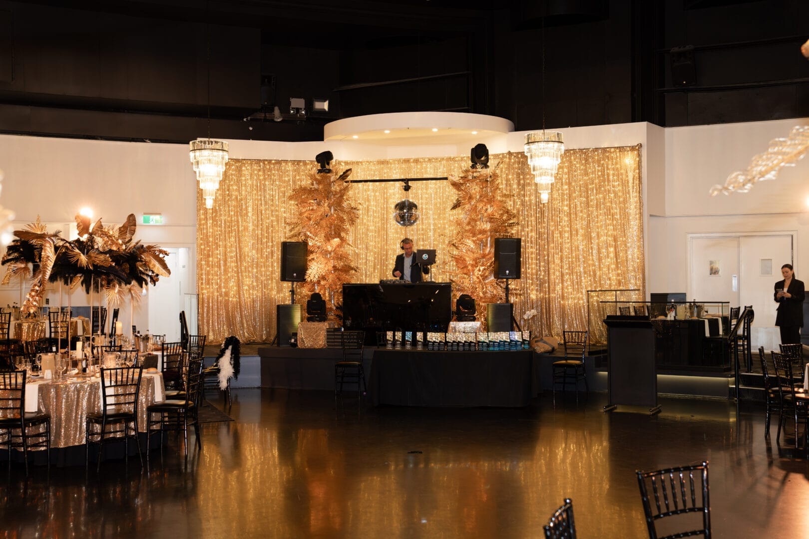 dj area at 1920s themed end of year gala with gold drape and fairy lights and gold leaf installation